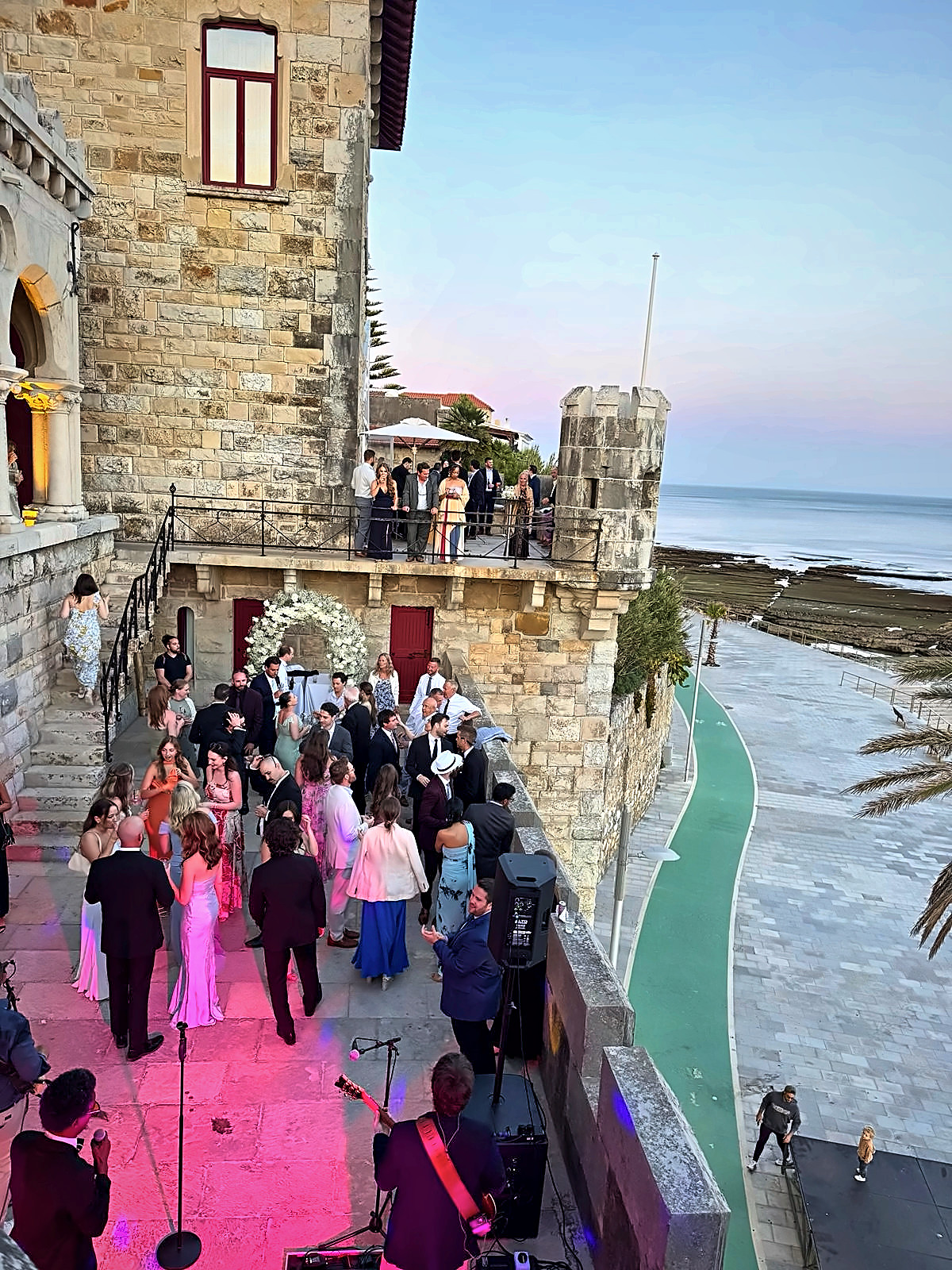 Wedding guests at sunset by the sea, with a PhotoLand booth